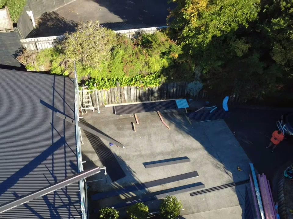 Freshly roofed dark hip roof from directly above, scaffold still up along the edge