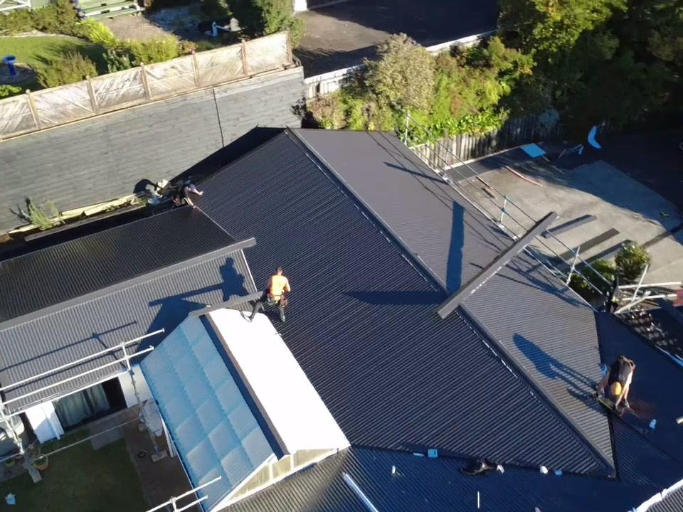 Roofer working at the ridge of a partly re-roofed house