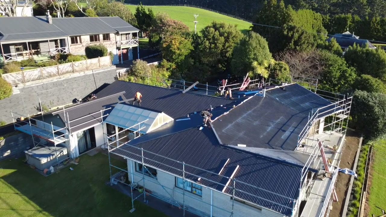 Single storey Taranaki home fully scaffolded for a re-roof, with new dark sheets already on